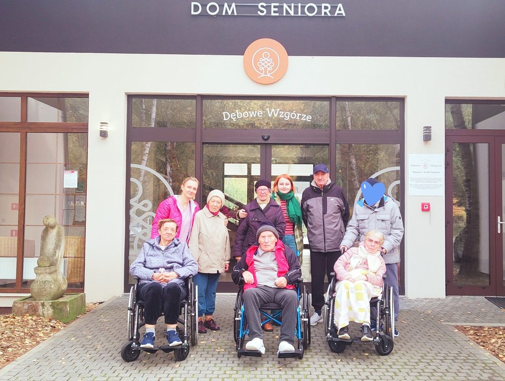 Seniorzy przed wejściem do Domu Seniora Dębowe Wzgórze przed wyruszeniem na spacer z legendą.